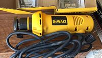 DeWalt DW660 heavy duty cut-out tool with power cord shown on wooden surface with original yellow box partially visible.