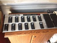 Front view of the Behringer FCB1010 MIDI Foot Controller showing 10 footswitches numbered 1 to 10 with some scratches and dust.