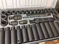 Open plastic case with map printed on lid, showing sizes and placement of sockets and tools. Matte black impact sockets arranged inside.