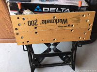 Side view of the wooden top and black metal frame of the Workmate 200 work bench