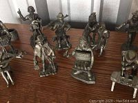 Group of pewter figurines displayed on a wooden surface, various characters including musicians and historical figures.