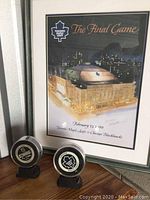 Framed print and two hockey pucks displayed on a shelf.