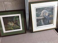 Two framed wildlife prints by Gordon Pynn, one of a raccoon and one of a chipmunk, placed on a table. Frames show wear with scratches and dings.