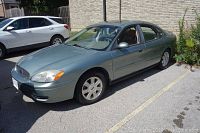 Driver’s side front view of green sedan on pavement