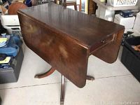Drop leaf wooden table with two leaves down in a closed position shown from above