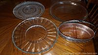 Three glass platters and one silver-trimmed glass nut server on table.