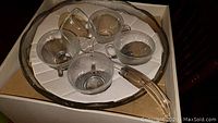 Clear glass punch bowl and 4 cups with handles arranged in a box, showing the textured design and handle details