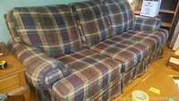 Full view of the large plaid couch showing the cushioned back, seat, and rolled arms with matching fabric upholstery.