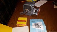 Keystone Capri 8mm movie camera on table with instruction booklet and Kodachrome film box, showing overall condition and included items.