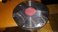 Stack of vintage 78 RPM vinyl records shrink-wrapped together on a wooden surface.