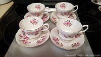 Four Royal Albert bone china teacups each with matching saucer featuring pink rose floral pattern and gold accents, displayed on a neutral background.