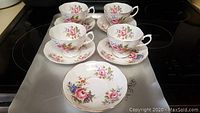 Four Royal Albert teacups and five matching saucers in floral pattern on a surface.