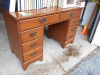 Front angle photo showing the desk's six drawers, metal handles, and some minor scratches on the wood surface.