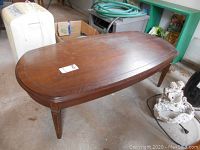 Front and side angle showing the shape, surface wear, and leg details of the vintage coffee table.