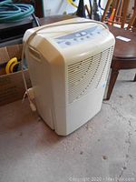 Front angle view of white Maytag dehumidifier showing vented front and power cord on side.