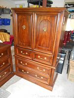 Front view of two-piece highboy dresser showing paneled cabinet doors above two small and two larger drawers