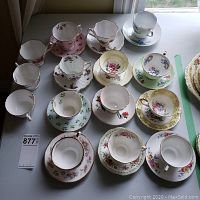 Overview photo of 14 bone china cups and matching saucers with various floral patterns on a tabletop, showing condition and decorative details