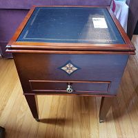 Front view of Bombay leather topped end table showing wood frame, decorative inlay on drawer and front panel, and round knob handle.
