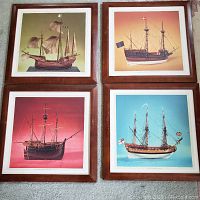 Four framed prints showing model ships against different colored backgrounds