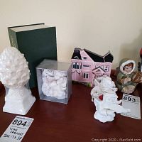 Group photo of all items on a wood surface including boxed Snow Baby, pottery angel, ceramic angels, and painted wood house