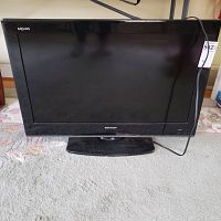 Front view of the Sharp Aquos 32 inch TV with stand, showing the full screen and base.