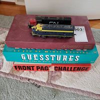 Photo showing stacked board games Scrabble, Guesstures, Front Page Challenge with two electric model train engines on top.