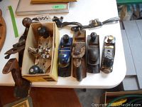Overview of six metal planes and spokeshaves arranged on a white table