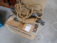Block and tackle coiled on cardboard boxes showing the full length of the rope and metal pulleys.