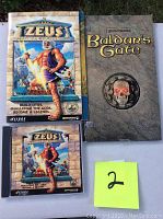 Photo showing Zeus Master of Olympus PC game jewel case, manual, and Baldur's Gate manual.