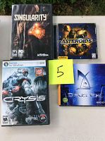 Photo showing four PC video games in their cases: Singularity, Asteroids, Crysis, and Deus Ex with a yellow sticky note '5' on top.