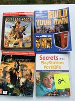 Four Prima official strategy guides arranged on a white surface: Wargasm, Build Your Own High Performance Gamers Mod PC, Outcast, and Secrets of the PlayStation Portable.