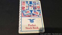 Full view of the Pocket Stock Book cover featuring USA flags and stamps in red, white, and blue colors with handwritten notes on it.
