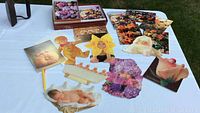Photo showing group of die-cut Anne Geddes shaped cards depicting babies and floral motifs.
