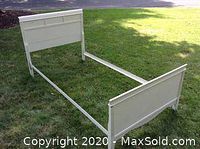 Vintage white twin sleigh bed frame set up outside on grass showing full frame including headboard and footboard.