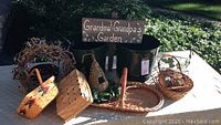 Overview of the garden items including sign, baskets, birdhouse, and two green pots