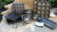 Photo showing two muffin pans, two square cake pans, two oblong brownie pans, three nesting stainless steel mixing bowls with handles, set of biscuit cutters, and a cooling rack.
