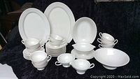 Full view of the Syracuse China completer set showing all items with two large oval platters, one small oval platter, various bowls and creamers, 12 cups and saucers stacked.