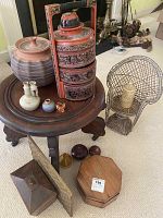 Wood round table top with pottery bowl, Asian style stacking boxes, mini rattan chair, and various wood and metal boxes arranged around