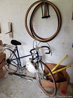 Photo of blue Raleigh road bike with drop handlebars next to spare bike tires hanging on the wall.
