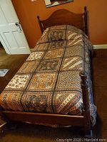 Full twin bed assembled with bedspread covering mattress area.