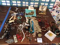 Full overview of assortment of costume jewelry showing various necklaces, bracelets, and decorative pieces on a wooden table