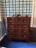 Full view of four-drawer serpentine front dresser against wall