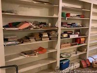Wide shot of shelves with assorted books, papers, board games, and boxes showing overall content density.