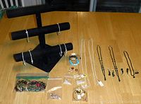 Photo showing bracelets on jewelry stand and organized jewelry items including loose beads, necklaces, and small earrings on table.