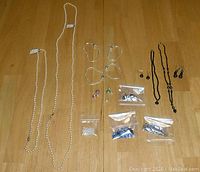 Full overview of the jewelry lot showing all items laid out on a wood surface.