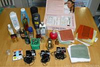 Full table view showing Jeunesse Spa Time Micro Vibration System box, toiletries, multiple face cloths, cologne bottles and hair elastics.