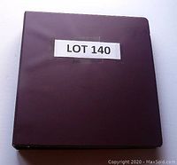 Photo showing a closed burgundy 3-ring binder album labeled 'LOT 140'.