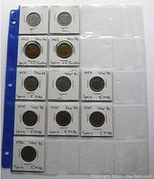 Photo of coins in individual holders on a coin storage sheet, showing 2, 2.5 and 5 Pesetas Spanish coins with star numbers and dates written on holders.