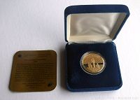 Photo of the proof coin in its original blue velvet-lined display case along with a certificate or descriptive card.