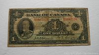 Front view of 1935 $1 Bank of Canada bill showing Osborne-Towers signatures and red serial numbers.